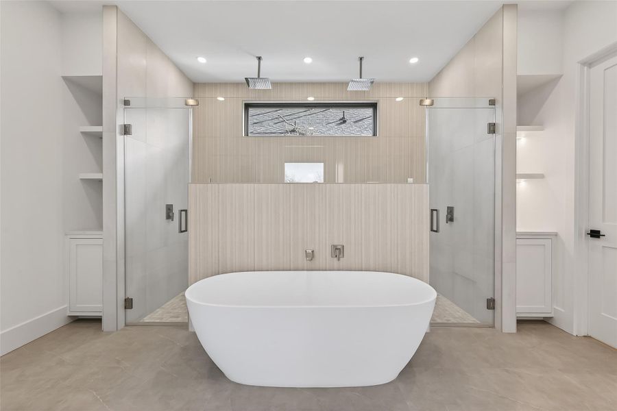 Luxurious bath with soaking tub, dual showers, and modern tile finishes.