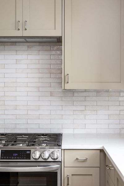 Kitchen with stainless steel range with gas cooktop, backsplash, range hood, and light stone countertops