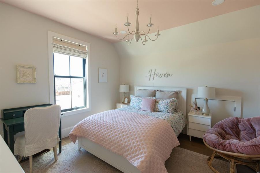 Bedroom featuring suspended lighting, lofted ceiling, and wood finished floors