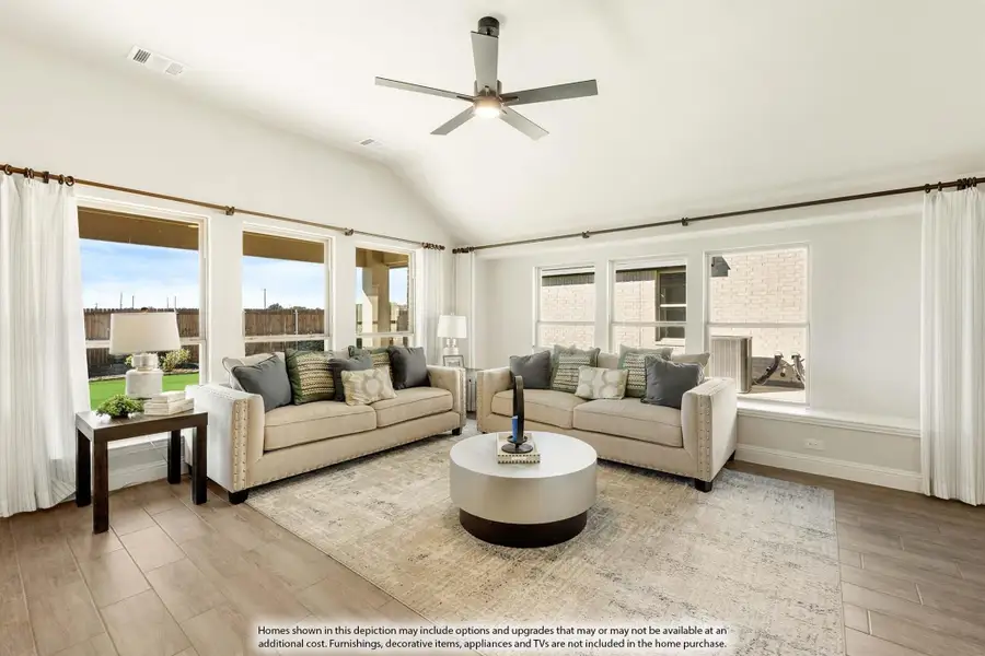Living room with vaulted ceiling, two beige sofas, round coffee table, and hardwood floors