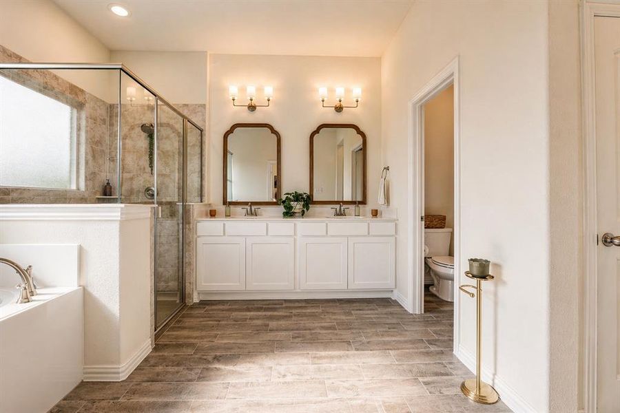 Bathroom featuring wood-finish tile flooring, a built-in soaking tub, and a separate glass-enclosed shower with tile surround