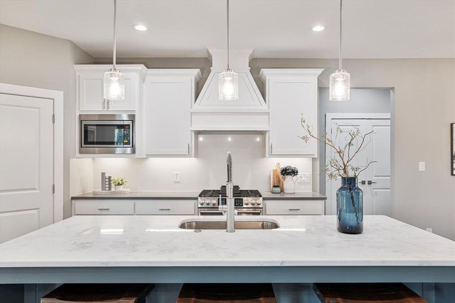 Kitchen with premium range hood, a center island with sink, a breakfast bar, and stainless steel microwave Kitchen with premium range hood, a center island with sink, a breakfast bar, and stainless steel microwave