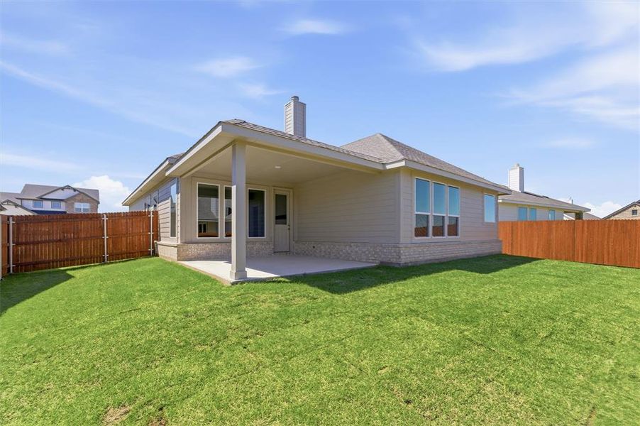 Back of house featuring a fenced backyard, a patio, brick siding, and a chimney