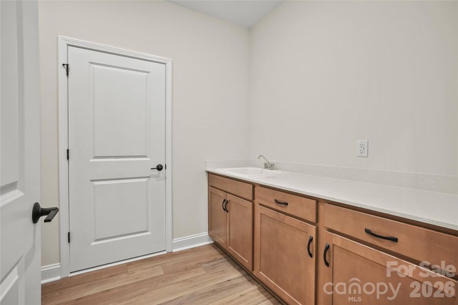 Spacious laundry room off the garage, featuring substantial storage and a utility sink