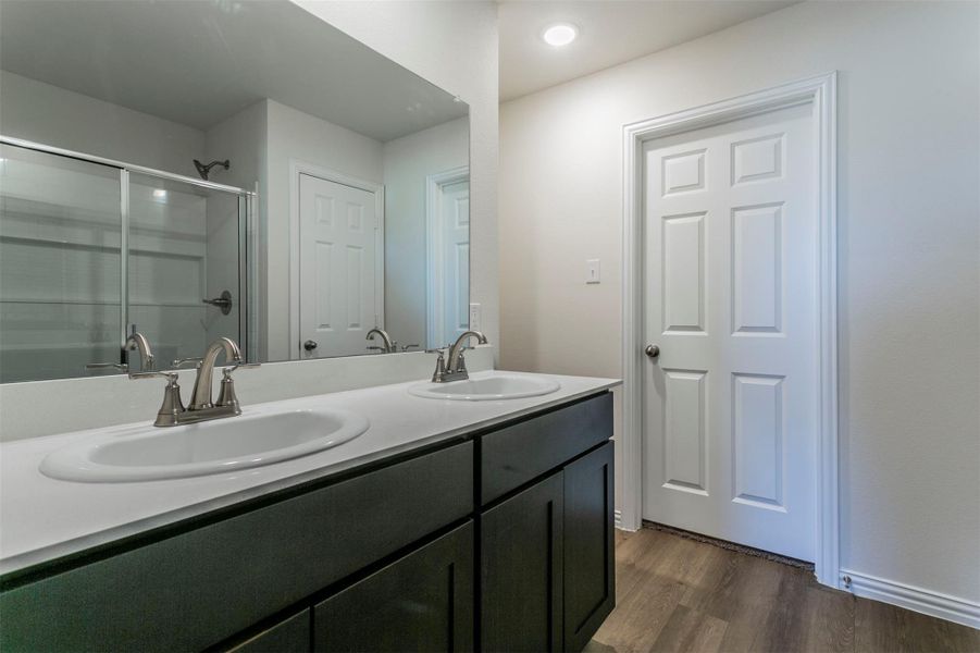 Full bathroom featuring double vanity, wood finished floors, a stall shower, and a sink Full bathroom featuring double vanity, wood finished floors, a stall shower, and a sink