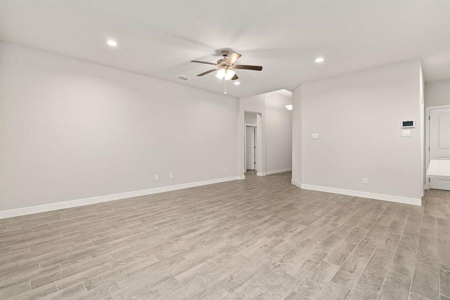 Empty room with ceiling fan and light wood-type flooring