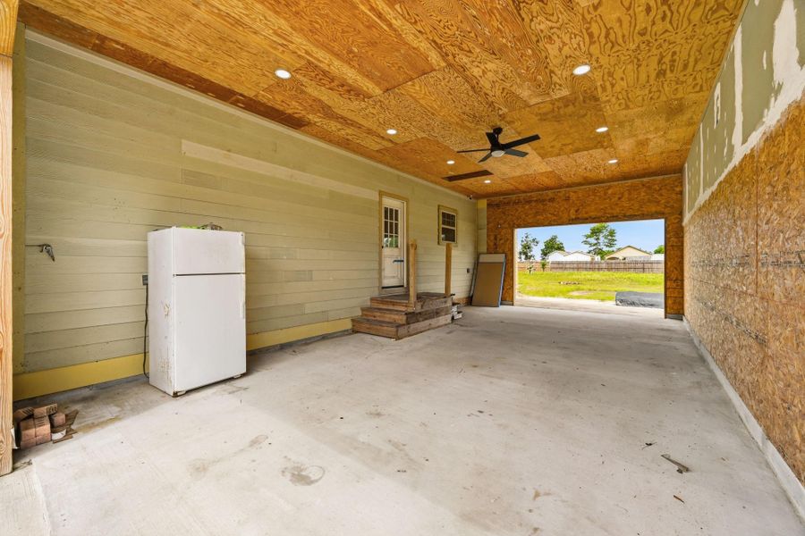 This oversized covered carport and workspace area offers exceptional versatility and functionality. Featuring durable concrete flooring, recessed lighting, and ceiling fans for added comfort, the space is ideal for covered parking, storage, hobbies, or workshop use. The expansive layout provides ample room for multiple vehicles, equipment, or outdoor entertaining possibilities.