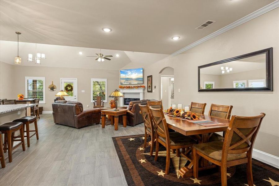 Dining area featuring lofted ceiling, light wood-style flooring, a fireplace, arched walkways, and recessed lighting Dining area featuring lofted ceiling, light wood-style flooring, a fireplace, arched walkways, and recessed lighting