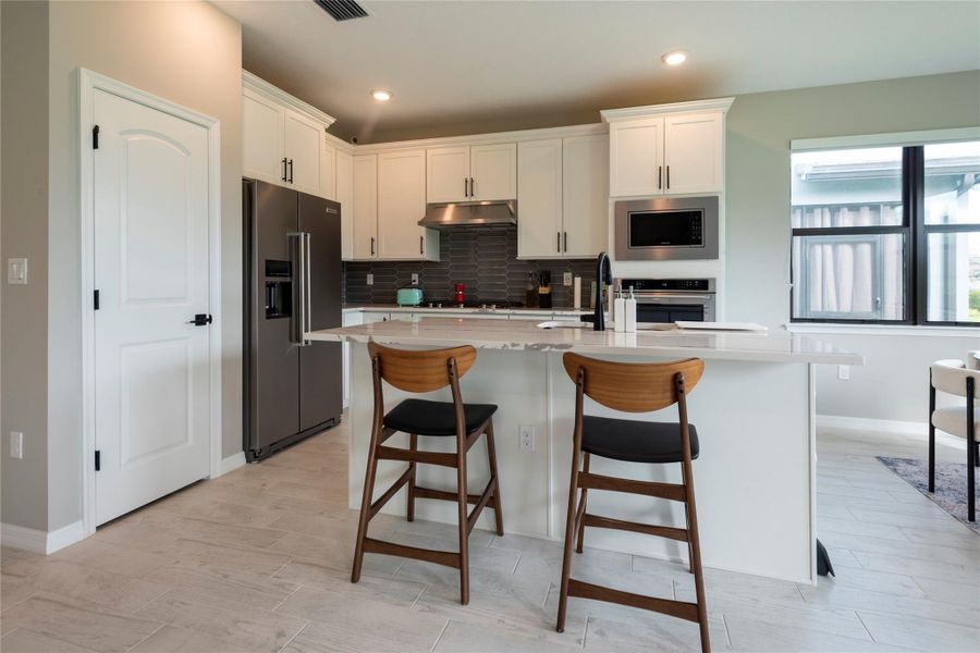 Top of the line Kitchen with large 42" wood cabinets, staineless steel appliances, quartz countertops, kitchen island with snack barcounter, wall oven and walk-in pantry