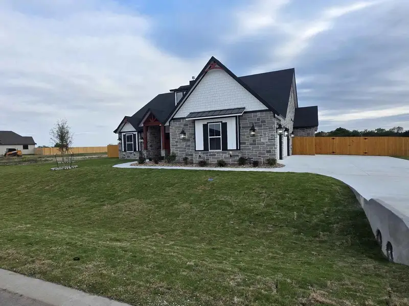 Craftsman-style home featuring a standing seam roof, stone siding, concrete driveway, and an attached garage Craftsman-style home featuring a standing seam roof, stone siding, concrete driveway, and an attached garage