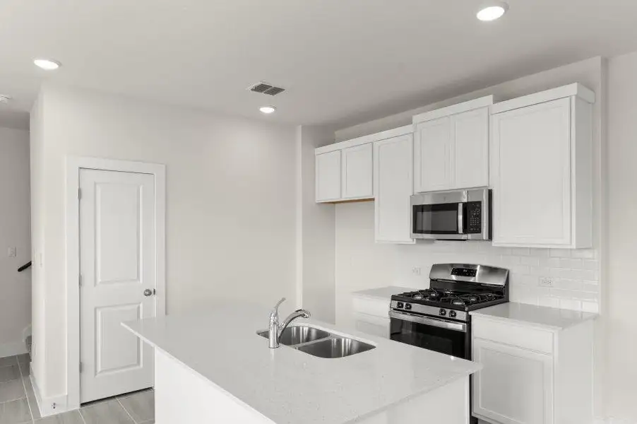 A well-appointed kitchen showcasing a center island, modern appliances, and crisp white cabinetry.