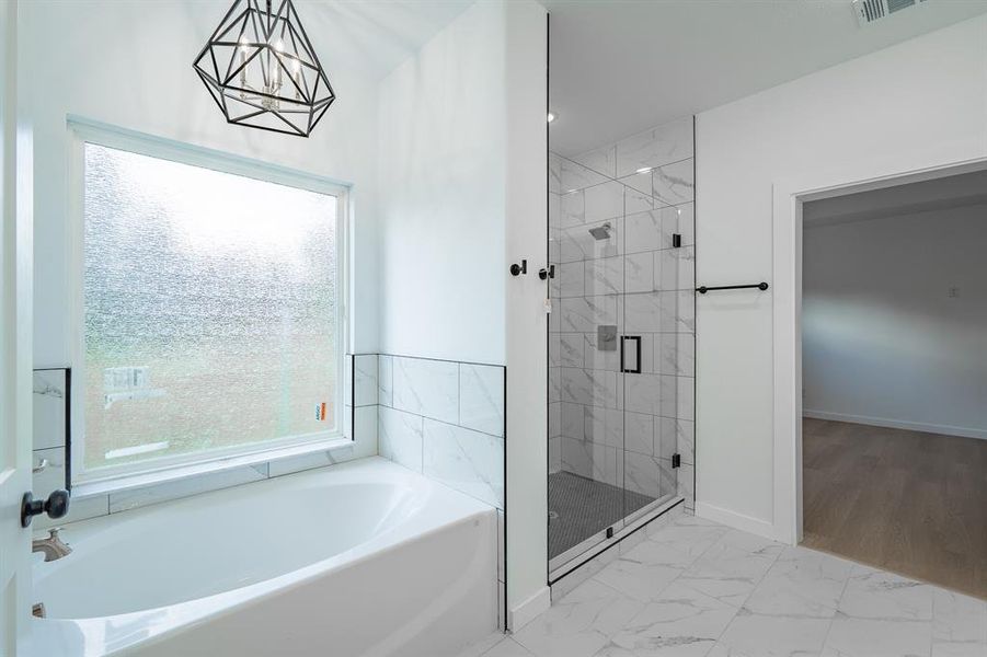 Bathroom with a bath, a shower stall, marble look tiles, and a chandelier Bathroom with a bath, a shower stall, marble look tiles, and a chandelier