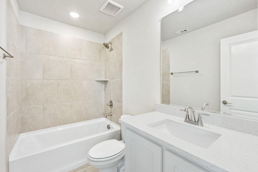 Bathroom with tiled tub-shower combo, white vanity with quartz countertop, and large mirror Bathroom with tiled tub-shower combo, white vanity with quartz countertop, and large mirror