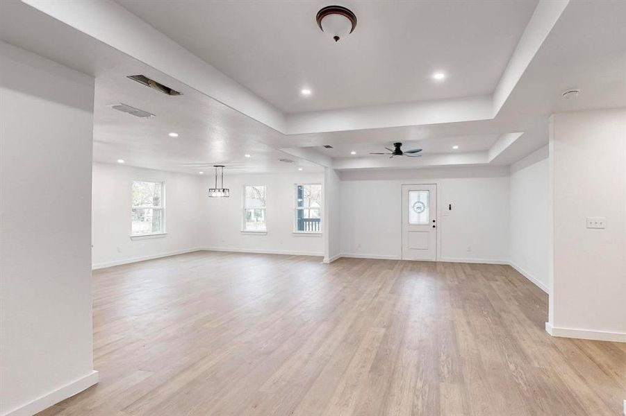 Unfurnished living room featuring a tray ceiling, light hardwood / wood-style flooring, and ceiling fan