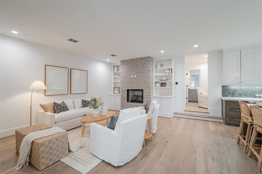 Living room with a brick fireplace and light hardwood / wood-style floors