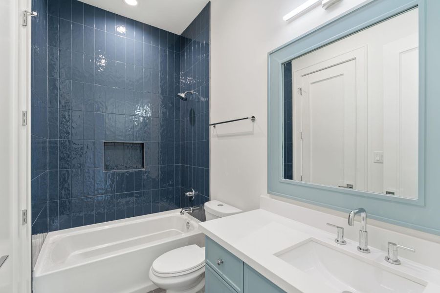 Another secondary bath includes a tub and shower combination with full-height tile surround, paired with a quartz vanity and modern fixtures.
