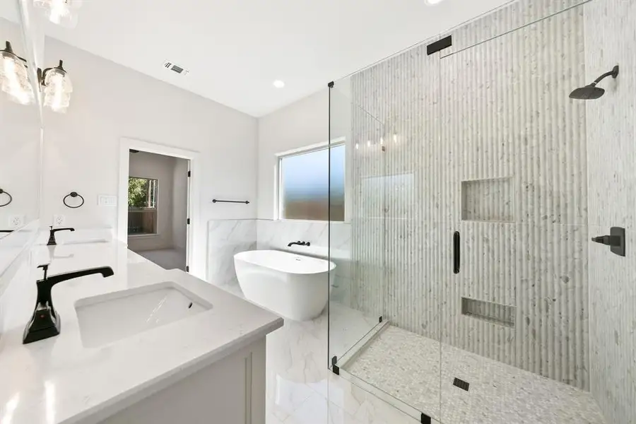 Bathroom with double vanity, a soaking tub, a shower stall, light marble finish flooring, and recessed lighting