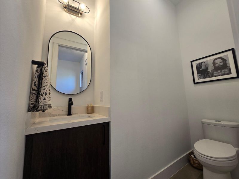 Smooth walls and a modern vanity with stone counters define this powder room.