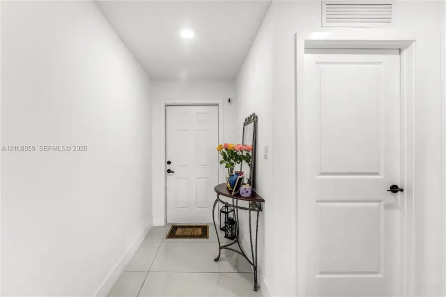Entryway featuring large-format ceramic tile flooring, recessed lighting, and a six-panel front door with matte black hardware