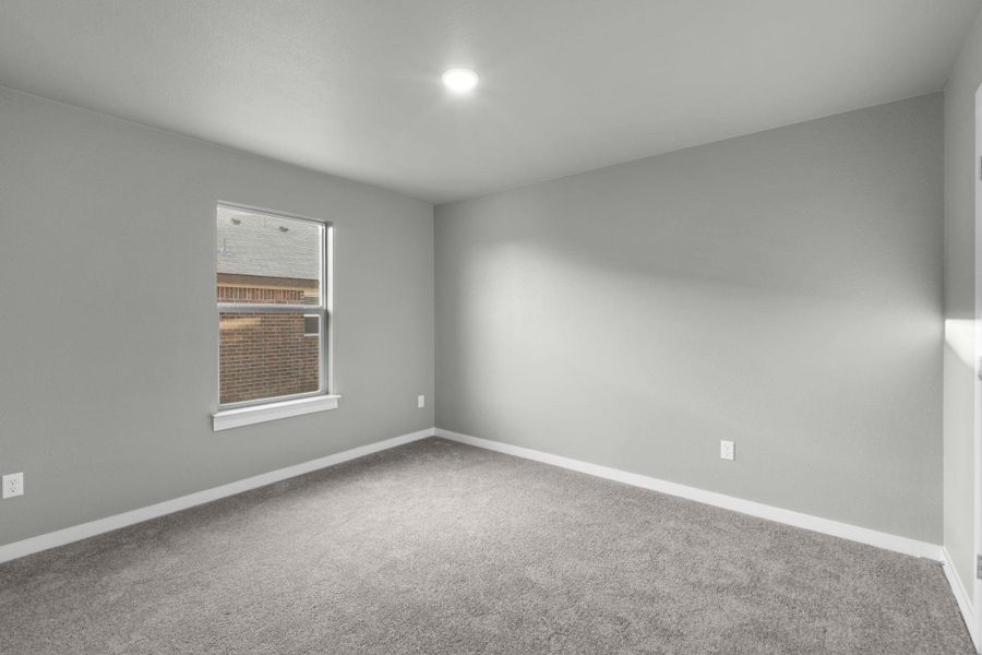 A well-lit bedroom features plush carpeting and a bright window.