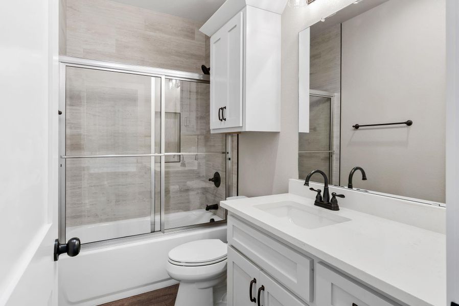 Bathroom featuring vanity and bath / shower combo with glass door