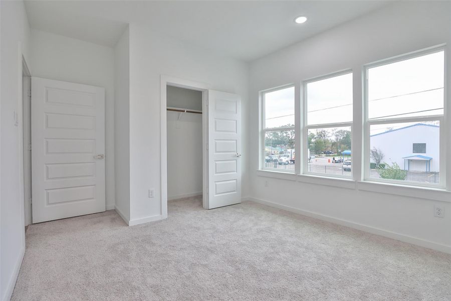 Bright and welcoming guest bedroom featuring ample natural light and a spacious closet.
