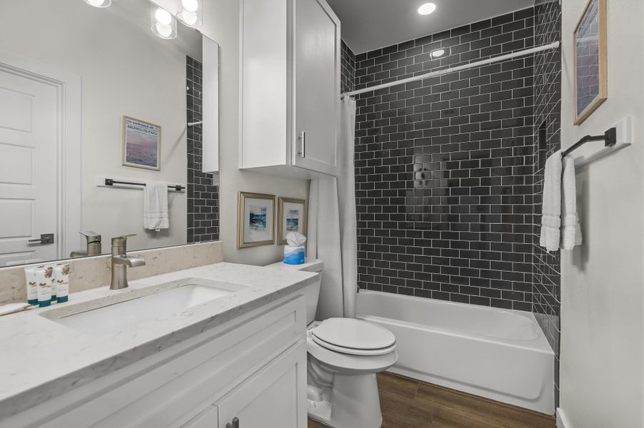 Full bath featuring dark wood-style flooring, vanity, and shower / bath combination with curtain Full bath featuring dark wood-style flooring, vanity, and shower / bath combination with curtain