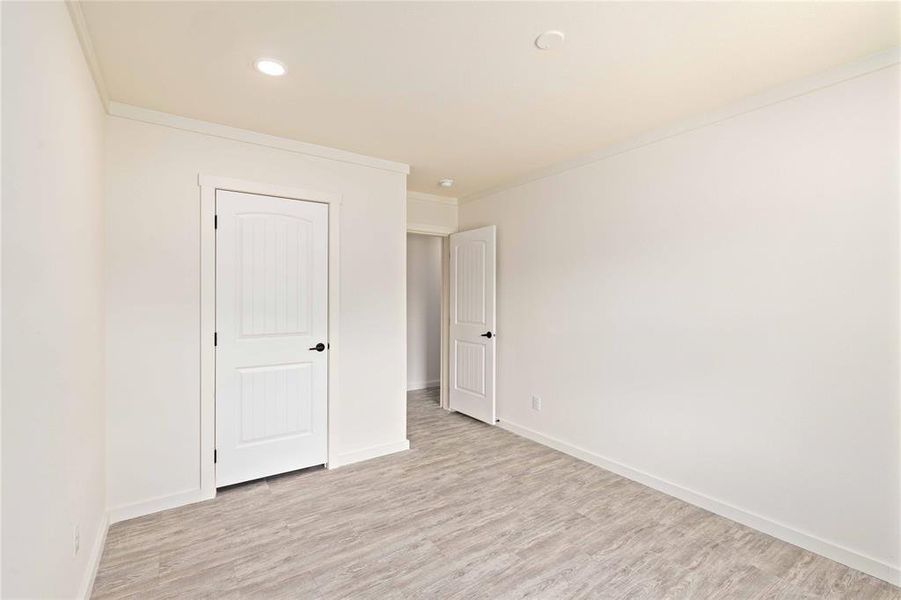 Interior room featuring light wood-finish flooring, white walls, and a recessed ceiling light
