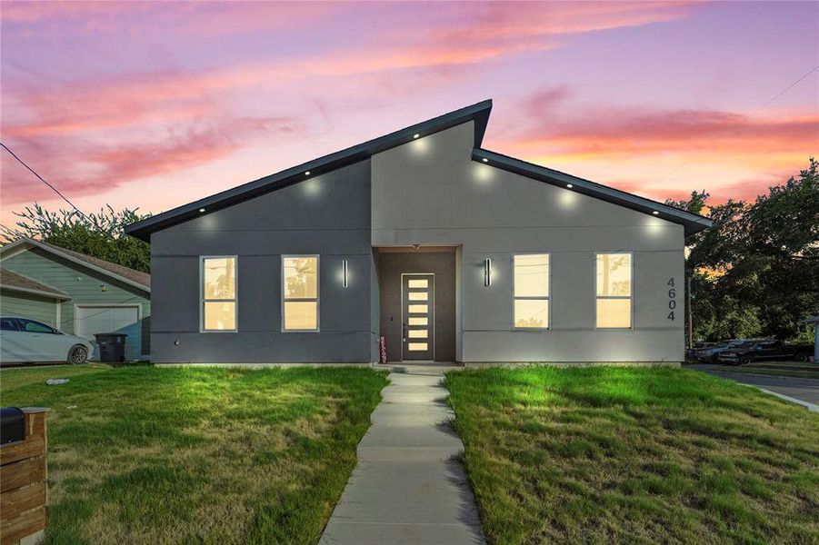 Modern home featuring stucco siding and a front yard