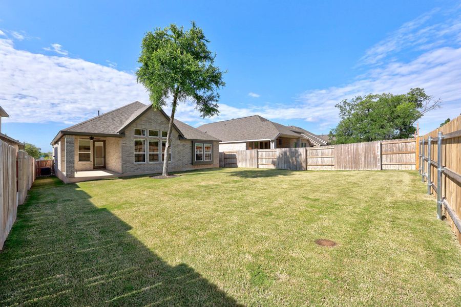 Back of property featuring a fenced backyard, brick siding, a patio, and a shingled roof