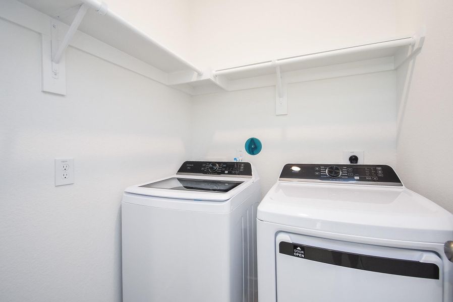 This bright utility room easily welcomes New dual laundry appliances, with handy storage above.