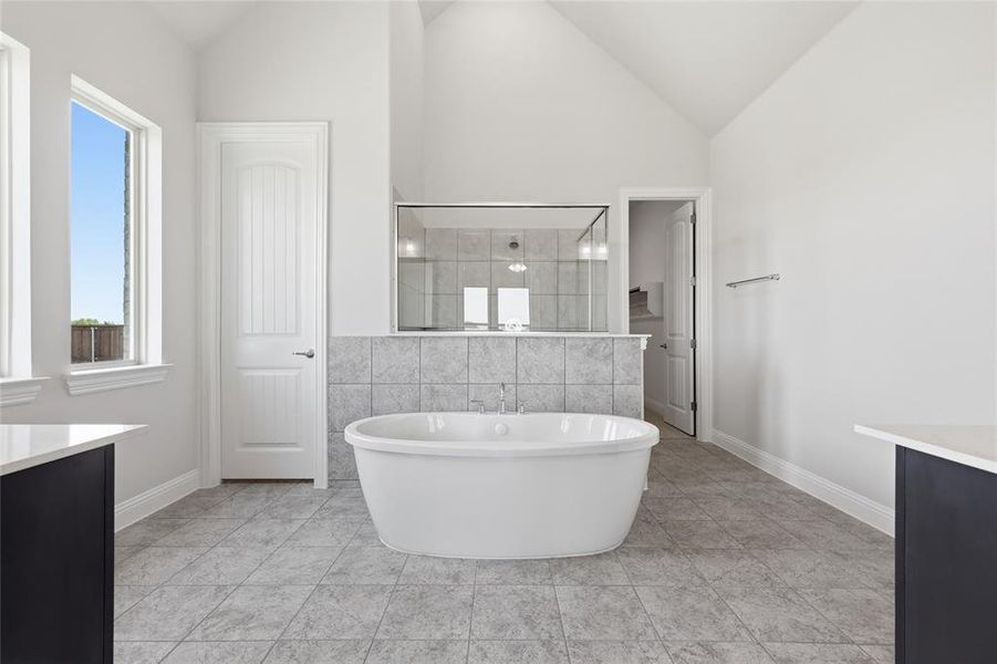 Bathroom with vanity, a shower stall, a soaking tub, vaulted ceiling, and tile walls Bathroom with vanity, a shower stall, a soaking tub, vaulted ceiling, and tile walls