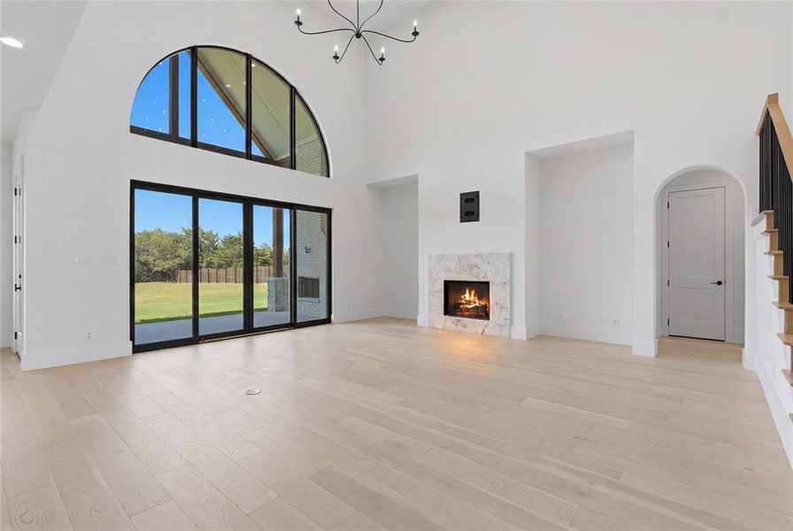 Spacious living area featuring a vaulted ceiling, wood-finish flooring, and a fireplace with a stone surround