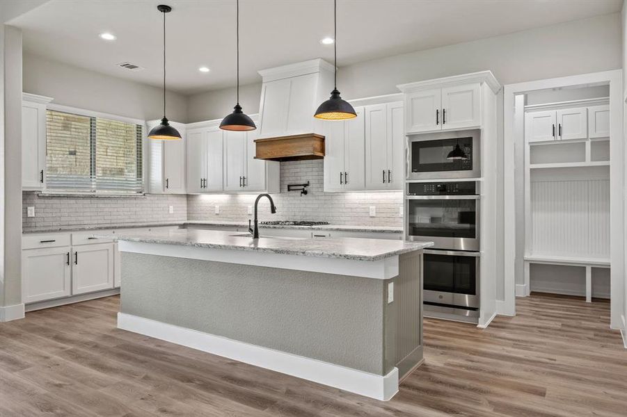 Kitchen featuring pendant lighting, light wood-style flooring, a kitchen island with sink, appliances with stainless steel finishes, and recessed lighting Kitchen featuring pendant lighting, light wood-style flooring, a kitchen island with sink, appliances with stainless steel finishes, and recessed lighting