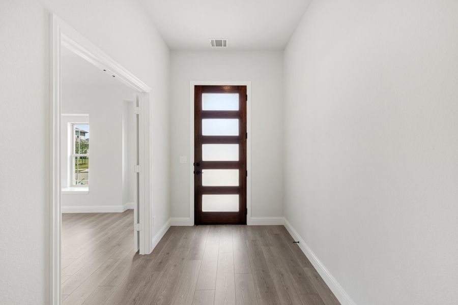 Entryway hallway with dark wood front door featuring glass panels and light gray hardwood floors Entryway hallway with dark wood front door featuring glass panels and light gray hardwood floors