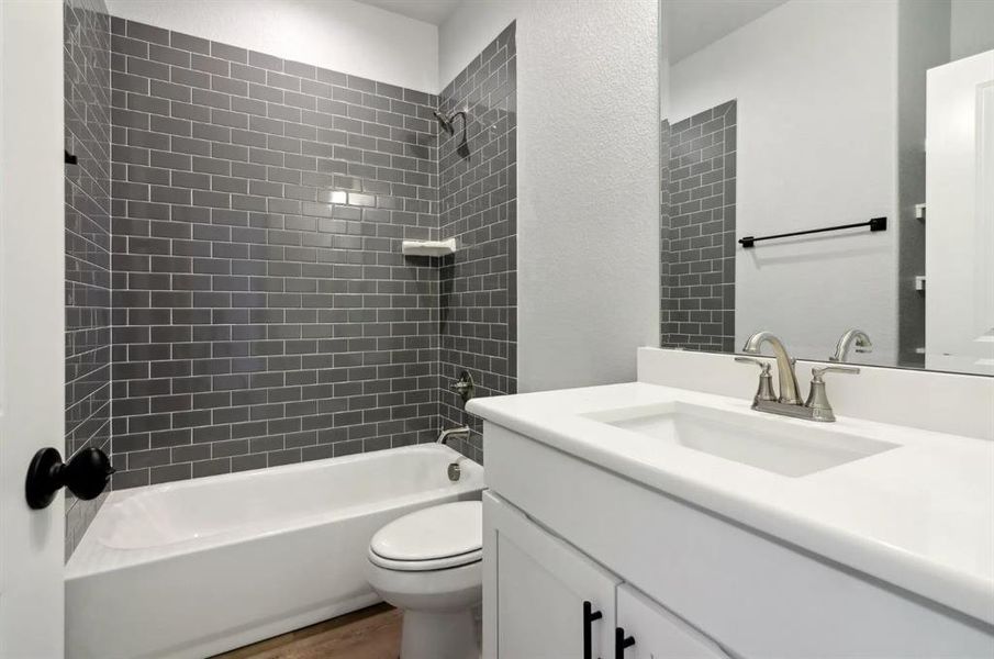 Full bathroom featuring vanity, toilet, tiled shower / bath combo, and hardwood / wood-style floors