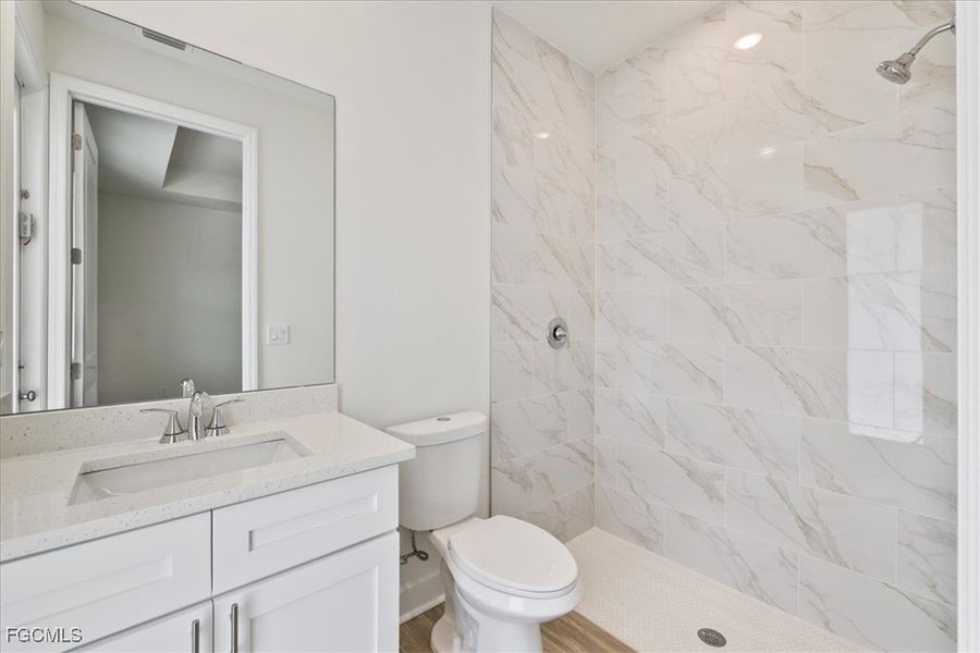 Bathroom featuring a marble finish shower and vanity