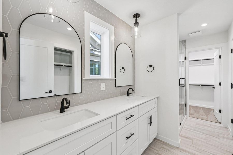 Bathroom featuring a walk in closet, double vanity, recessed lighting, a shower stall, and tasteful backsplash