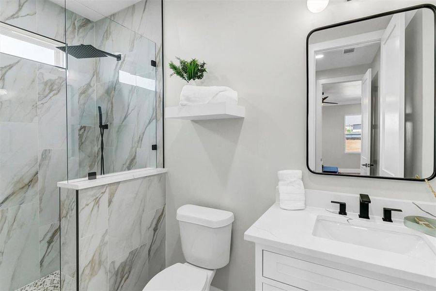 Bathroom featuring a healthy amount of sunlight, vanity, toilet, and an enclosed shower