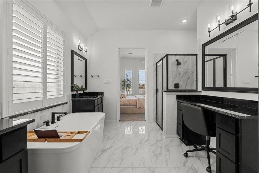 The luxurious primary en-suite bath features dual vanities, a walk-in shower, soaking tub, and separate his-and-her walk-in closets.