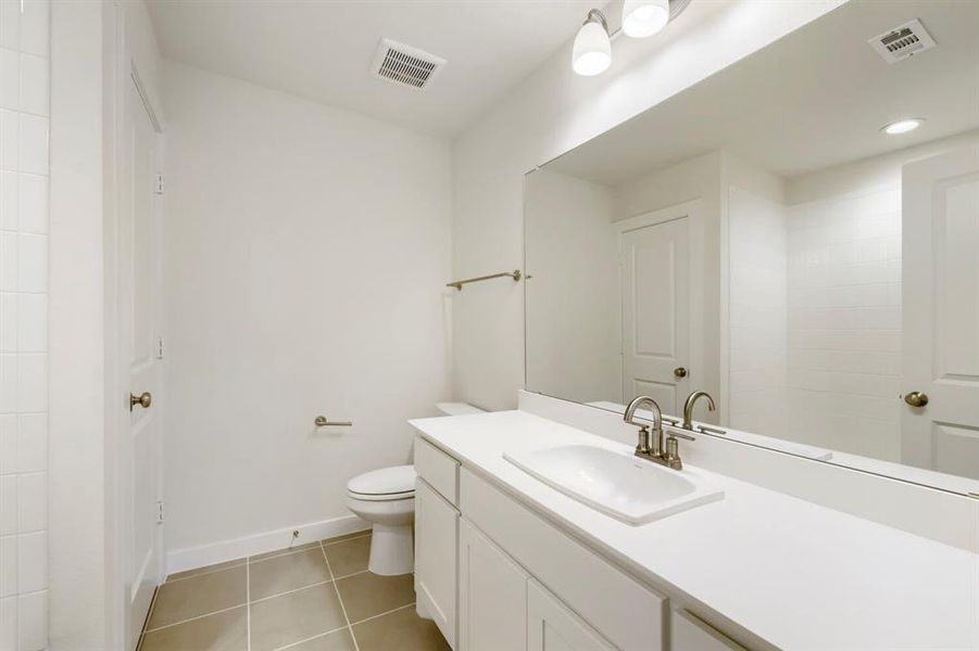 Bathroom featuring a white vanity with an integrated sink, brushed nickel faucet, and a large wall-mounted mirror Bathroom featuring a white vanity with an integrated sink, brushed nickel faucet, and a large wall-mounted mirror