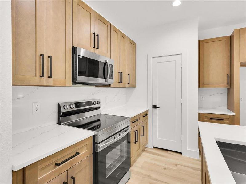 Kitchen with light stone counters, light wood-type flooring, and stainless steel appliances