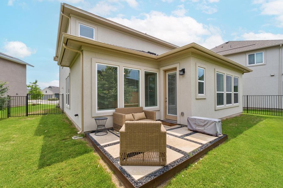 Rear view of property with a lawn, a fenced backyard, a patio area, and stucco siding Rear view of property with a lawn, a fenced backyard, a patio area, and stucco siding