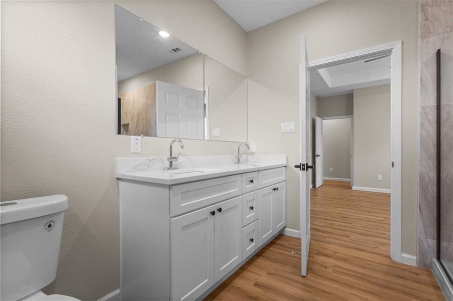 Bathroom with double vanity and light wood-style flooring