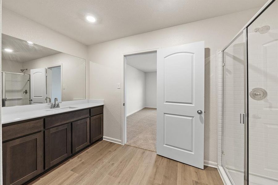 Full bath with baseboards, wood finished floors, a stall shower, and vanity