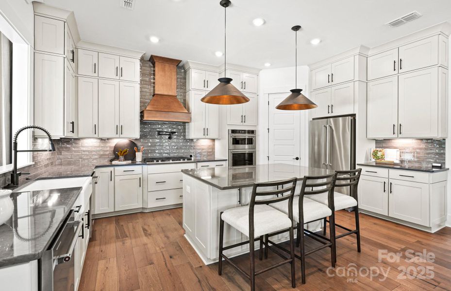 Beautifully Appointed Kitchen with Stacked Cabinets, Wood Hood, Kitchen Aid Appliances, Quartz Countertops, Upgraded Tile Backsplash and Under Cabinet Lighting.  Representative Photo.
