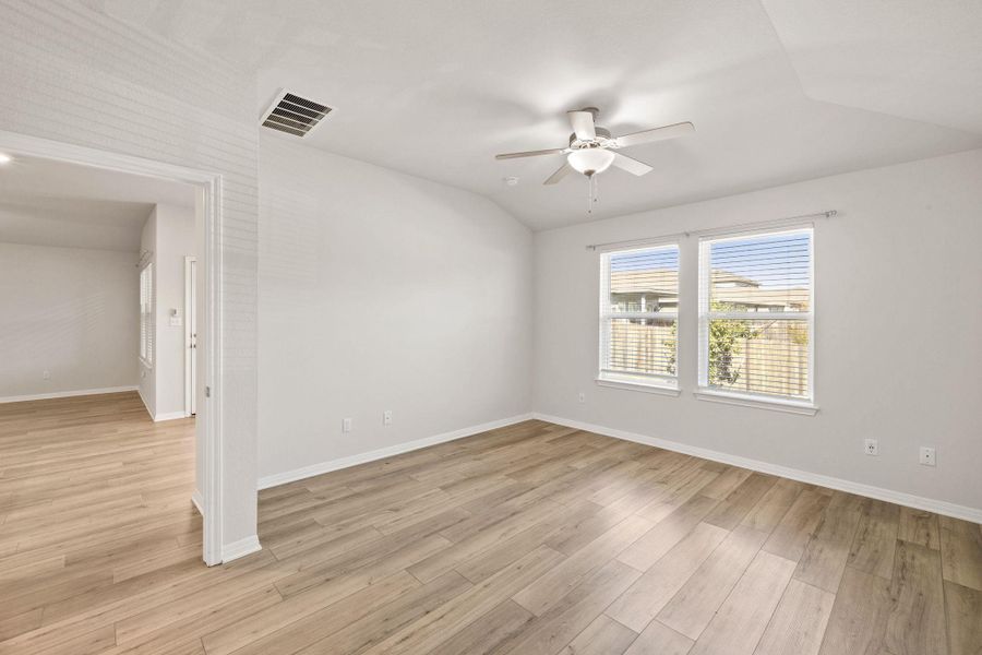 Unfurnished room with light wood finished floors, vaulted ceiling, and a ceiling fan Unfurnished room with light wood finished floors, vaulted ceiling, and a ceiling fan