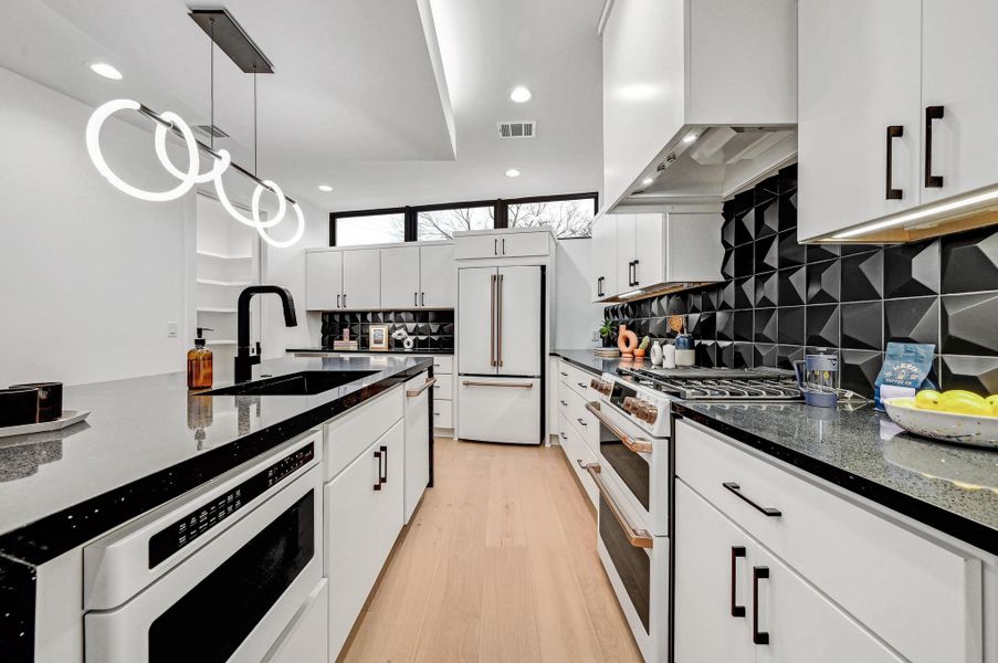Kitchen with dark stone countertops, white cabinets, backsplash, white appliances, and recessed lighting