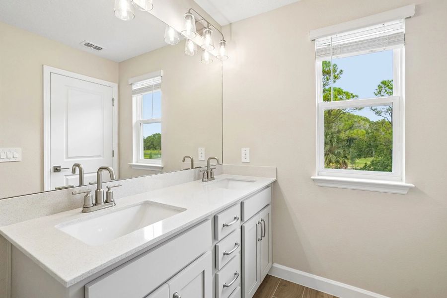 The primary bathroom featuring aspects of AW Collection® Milan also has double sinks and a window for natural lighting