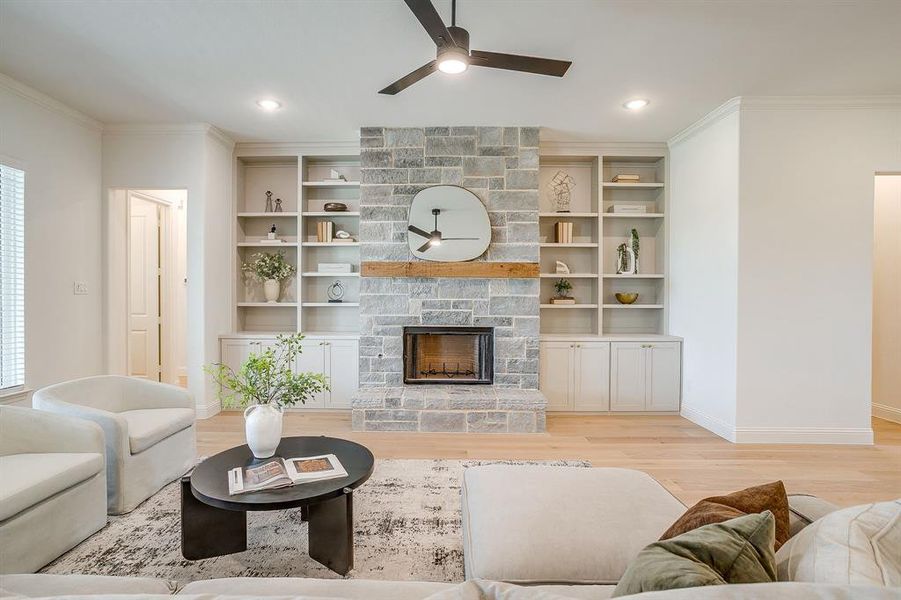 Living area with built in adjustable shelves, light engineered wood flooring, a stone fireplace with solid cedar mantle, ceiling fan, and french doors that open to a covered back patio. Living area with built in adjustable shelves, light engineered wood flooring, a stone fireplace with solid cedar mantle, ceiling fan, and french doors that open to a covered back patio.